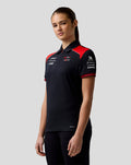Model wearing Official Haas Team women's short sleeve polo in dark fabric with red shoulder panels and a concealed zip placket.