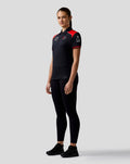 Profile of a female model wearing a dark Haas Team polo with red shoulder panels and sponsor logos on the chest