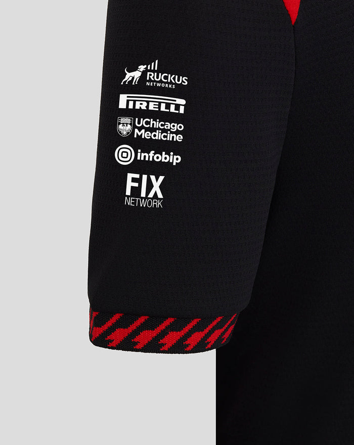 Close up of black Haas team junior driver T-shirt sleeve with RUCKUS NETWORKS PIRELLI UChicago Medicine infobip and FIX NETWORK logos and a red patterned cuff