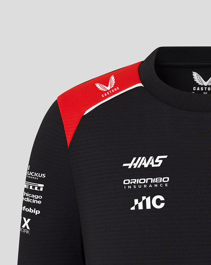Close up of Official Haas Team Junior Driver T Shirt with red shoulder panel, Castore logo on the shoulder, and Haas branding on the chest