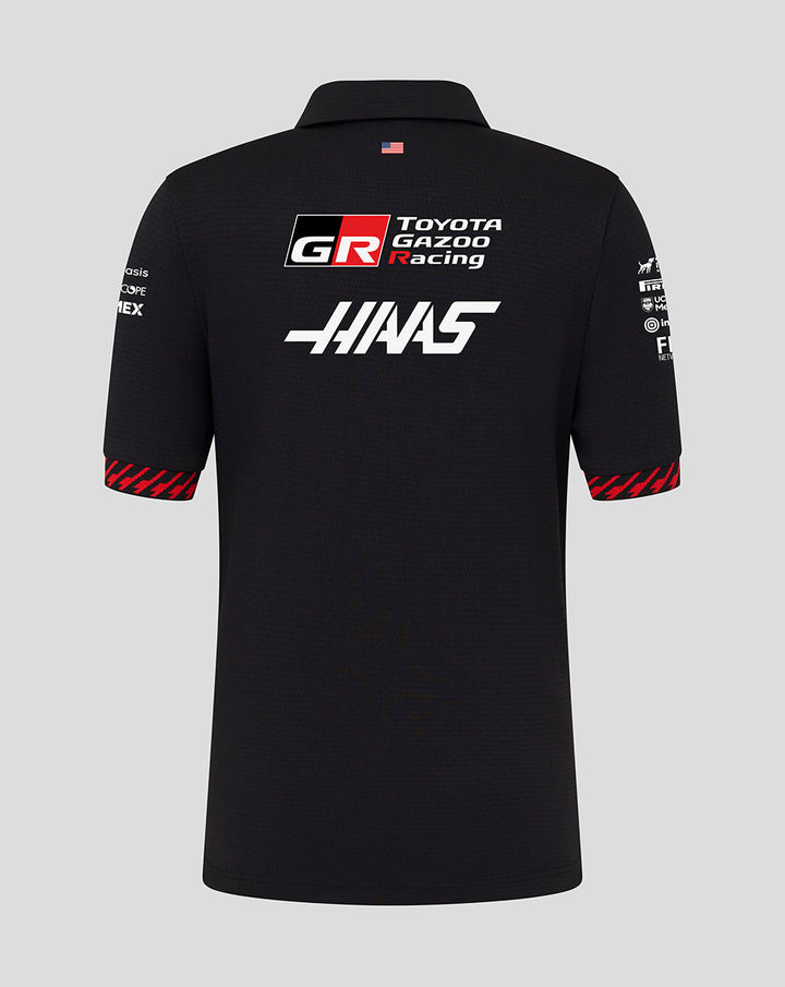 Back view of black Official Haas Team Junior Short Sleeve Polo Shirt with large Haas and Toyota Gazoo Racing logos and a small flag at the collar.