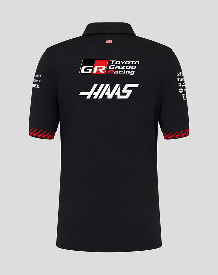 Back view of black Official Haas Team Junior Short Sleeve Polo Shirt with large Haas and Toyota Gazoo Racing logos and a small flag at the collar.