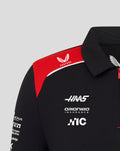 Upper torso of black Haas polo with a red shoulder panel and Castore branding on the shoulder and Haas logos on the chest