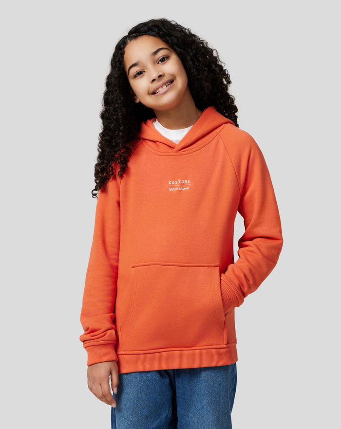 Young wearer in orange Castore Silverstone hoodie with chest logo and front kangaroo pocket