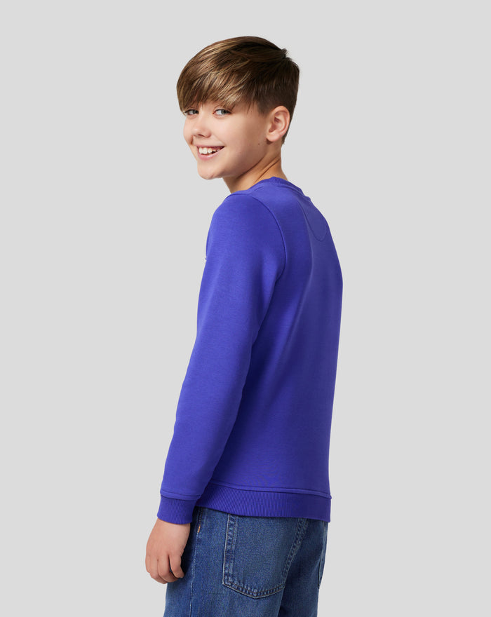 Side view of a junior in royal blue Silverstone Core Sweatshirt with chest print and jeans