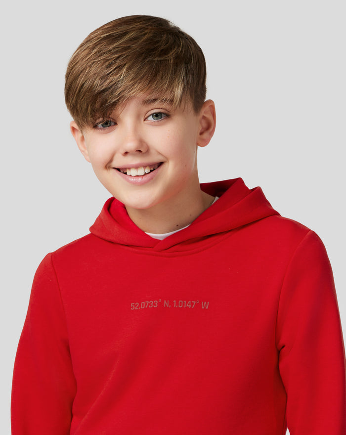 Back view of a person in a red hoodie with coordinates printed near the hem