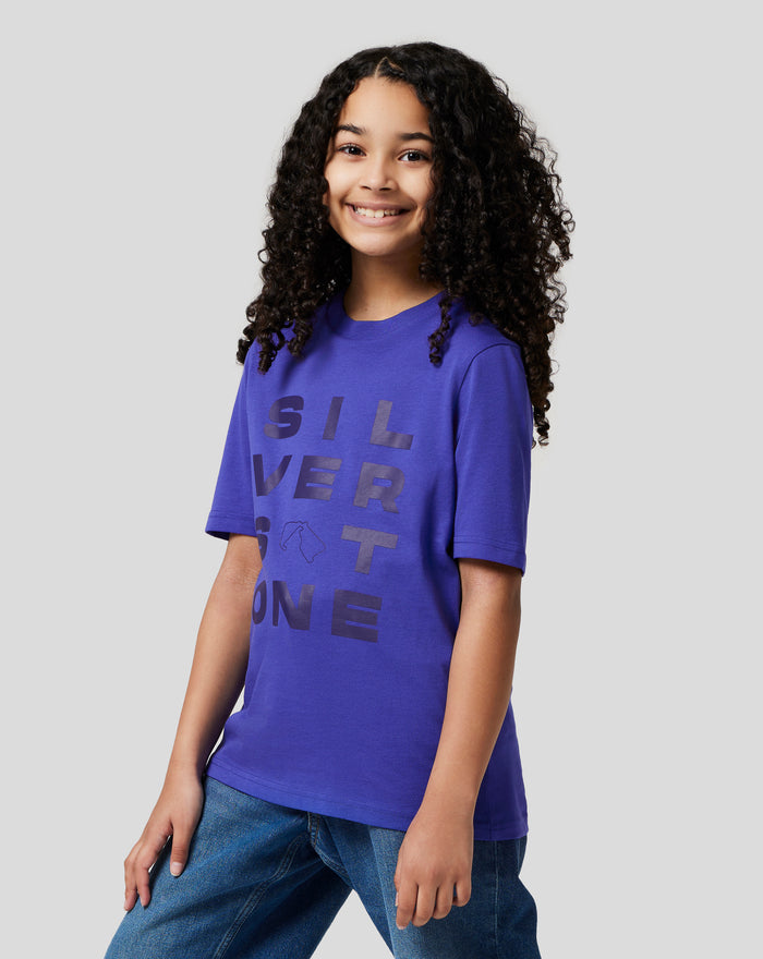 Smiling girl wearing a royal blue Junior Silverstone Core Graphic T Shirt with a large SILVER graphic on the front