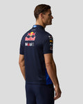 Back view of a man wearing a navy Oracle Red Bull Racing polo with large Red Bull and Mobil logos across the upper back.