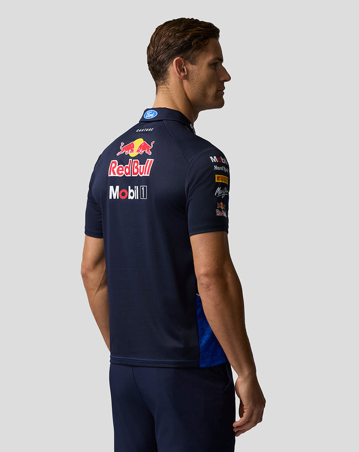 Back view of a man wearing a navy Oracle Red Bull Racing polo with large Red Bull and Mobil logos across the upper back.
