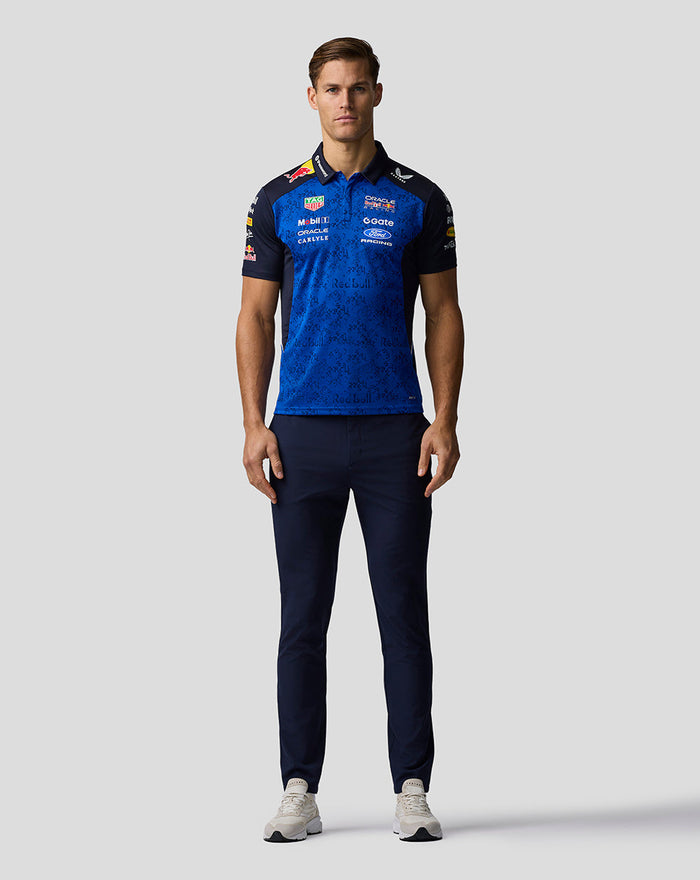 Full-body front view of a man wearing a navy and electric blue Oracle Red Bull Racing polo with sponsor logos.