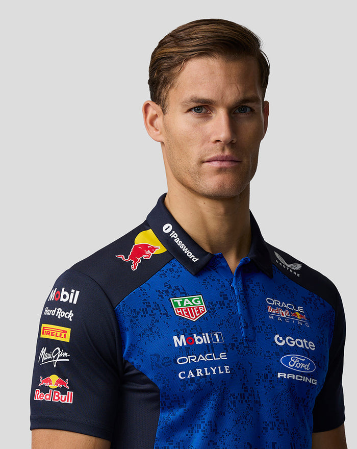 Close-up front view of a man wearing a blue Red Bull Racing polo showing the chest panel collar and sponsor logos.