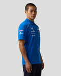 Side view of a male model in the blue Official Men’s BWT Alpine Formula One Team Polo Shirt with team logos on the chest.