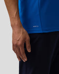Close up of a blue BWT Alpine polo on a wearer highlighting the AerTek logo at the hem.
