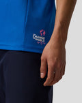 Back view of the blue BWT Alpine polo showing the Change the World sip by sip graphic on the lower back and sleeve logos.