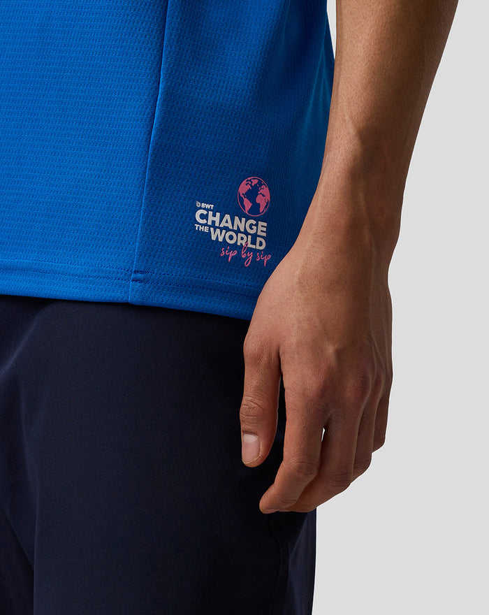 Back view of the blue BWT Alpine polo showing the Change the World sip by sip graphic on the lower back and sleeve logos.