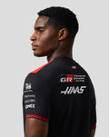 Rear view of a male model wearing a black Haas Team T Shirt with Haas and Toyota Gazoo Racing logos on the back.
