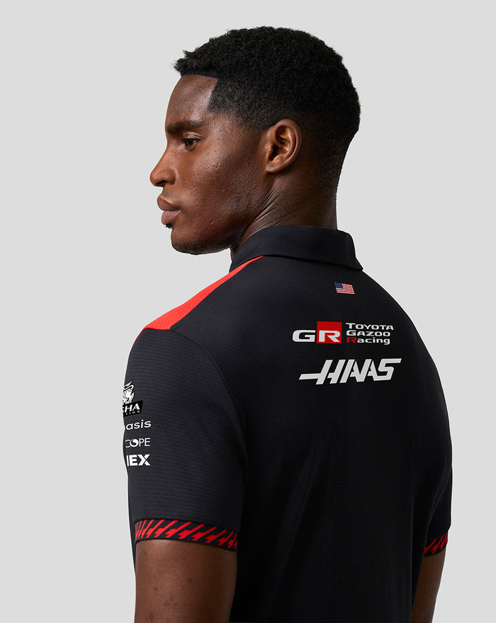 Back view of a model wearing the Haas Team Short Sleeve Polo with logos on back and red shoulder details