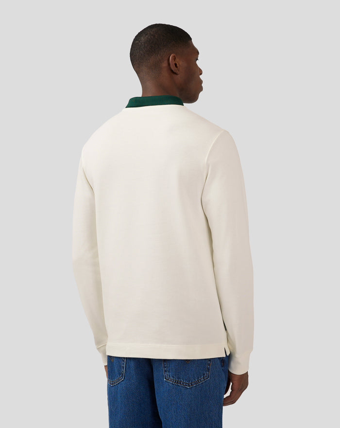 Back view of a cream long sleeve polo showing a teal patch near the lower back hem