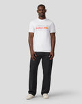 Full-body front view of a male model in a white Oracle Red Bull Racing T-shirt with large front graphic, paired with dark jeans and white sneakers.