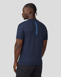 Back view of a man wearing a navy Core Track Graphic T-Shirt with a blue vertical stripe down the back.