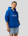 Female model in blue Silverstone Unisex Core Hoodie with chest graphic and relaxed stance