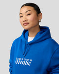 Model wearing blue Silverstone Core Hoodie with hood up and coordinates graphic on the chest.