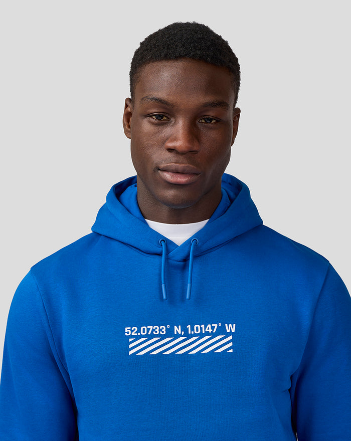 Close-up of a male model wearing the blue Silverstone Unisex Core Hoodie showing the chest graphic