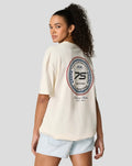 Angled back view of a model in a cream oversized T shirt with a circular patch on the back