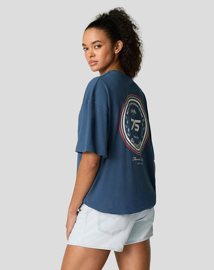 Back view of a model in a blue Sargasso oversized tee with a circular 75th anniversary Silverstone logo on the back