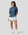 Front view of a model wearing a blue Sargasso oversized tee with a white chest logo graphic
