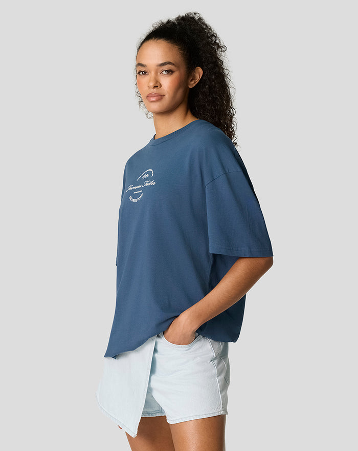 Side view of a model wearing a blue Sargasso Sea oversized T-shirt with a small chest graphic.