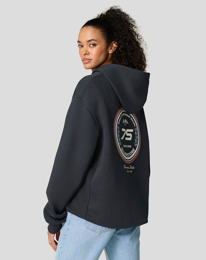 Model in dark navy Silverstone 75 Years oversized hoodie shown from the back with a circular emblem