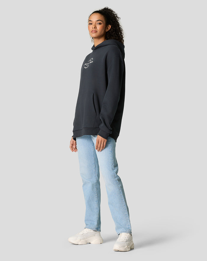Side profile of model in dark navy oversized hoodie featuring a small white chest logo