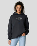 Model wearing dark navy oversized hoodie with front circular logo and kangaroo pocket