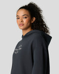 Profile view of woman in dark navy oversized hoodie with white logo on chest