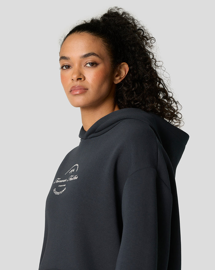 Profile view of woman in dark navy oversized hoodie with white logo on chest