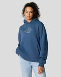 Front view of a model wearing a blue Sargasso Sea oversized hoodie with a circular chest patch.