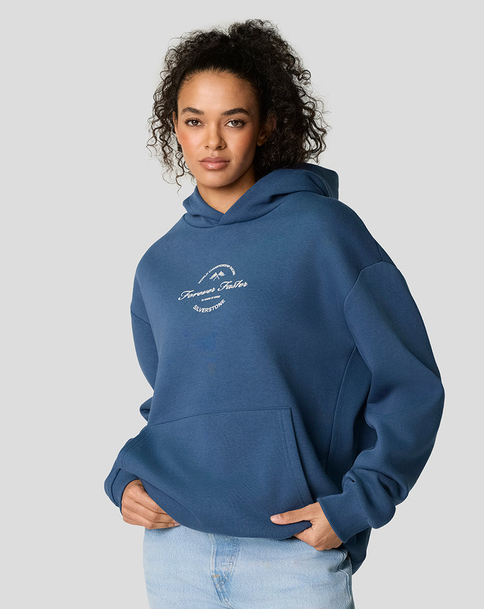 Model wearing blue oversized Silverstone hoodie with white Forever Faster logo on the chest