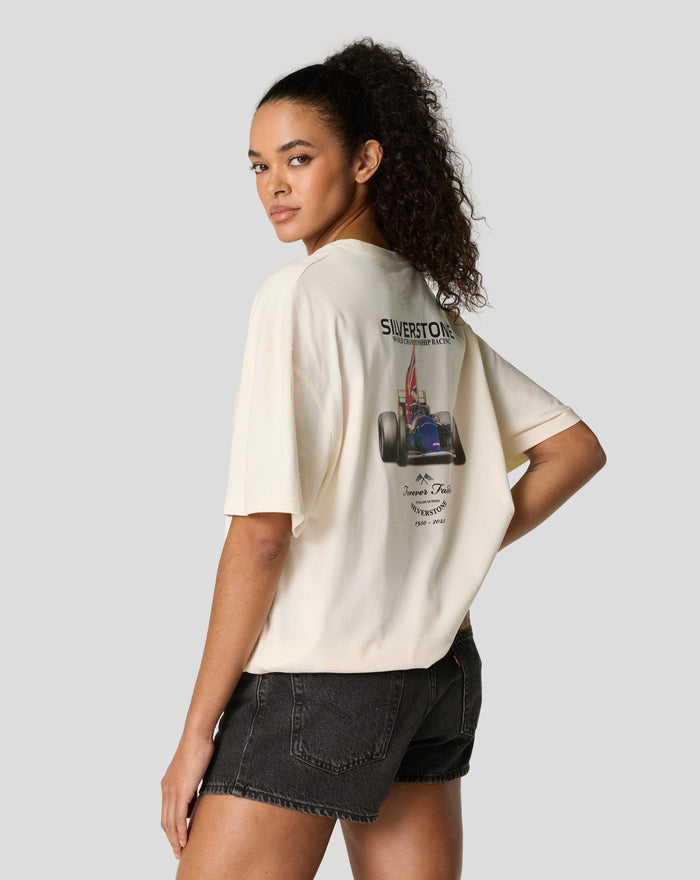 Model wearing an oversized egret tee turned to the side showing the back graphic of a race car and branding