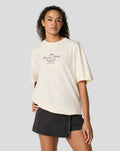 Person wearing cream oversized T shirt with Forever Faster crest on chest and dark denim mini skirt