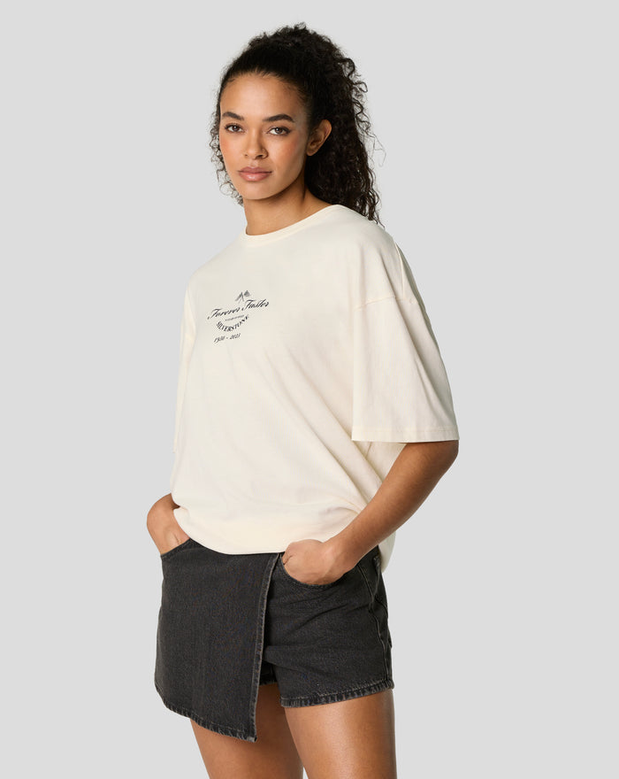 Side view of model in oversized egret tee showing the front chest graphic and relaxed fit