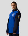 Front view of a woman wearing a blue Oracle Red Bull Racing Teamline water resistant jacket with hood and multiple sponsor logos.