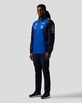 Front view of a male model in a blue and navy Oracle Red Bull Racing Teamline water resistant jacket with hood and sponsor logos