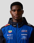Front view of a male model wearing the Night Sky Oracle Red Bull Racing Teamline water resistant jacket with branding on the chest.
