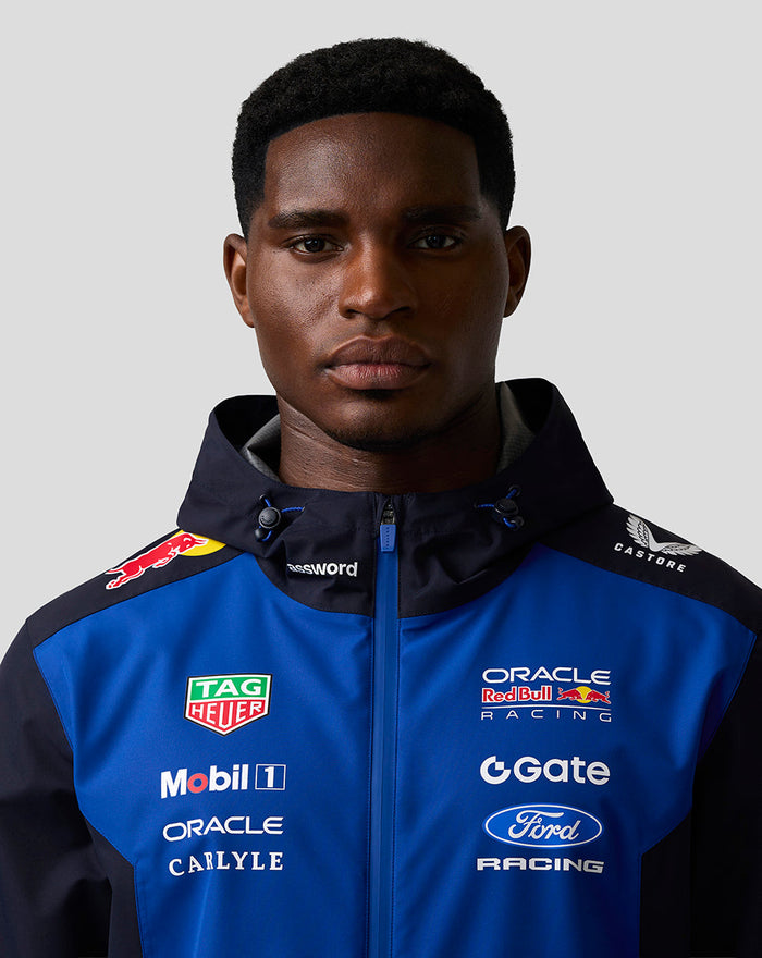 Front view of a male model wearing the Night Sky Oracle Red Bull Racing Teamline water resistant jacket with branding on the chest.