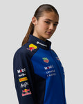 Three quarter view of a female model in the Oracle Red Bull Racing Teamline Soft Shell Jacket in night sky blue.
