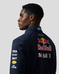 Side profile of a man in a navy Red Bull Racing Teamline soft shell jacket with a large Red Bull logo on the back and sleeve branding.