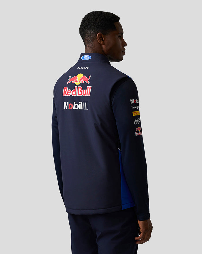 Back view of male model wearing navy Teamline Gilet with large Red Bull and sponsor logos on the back