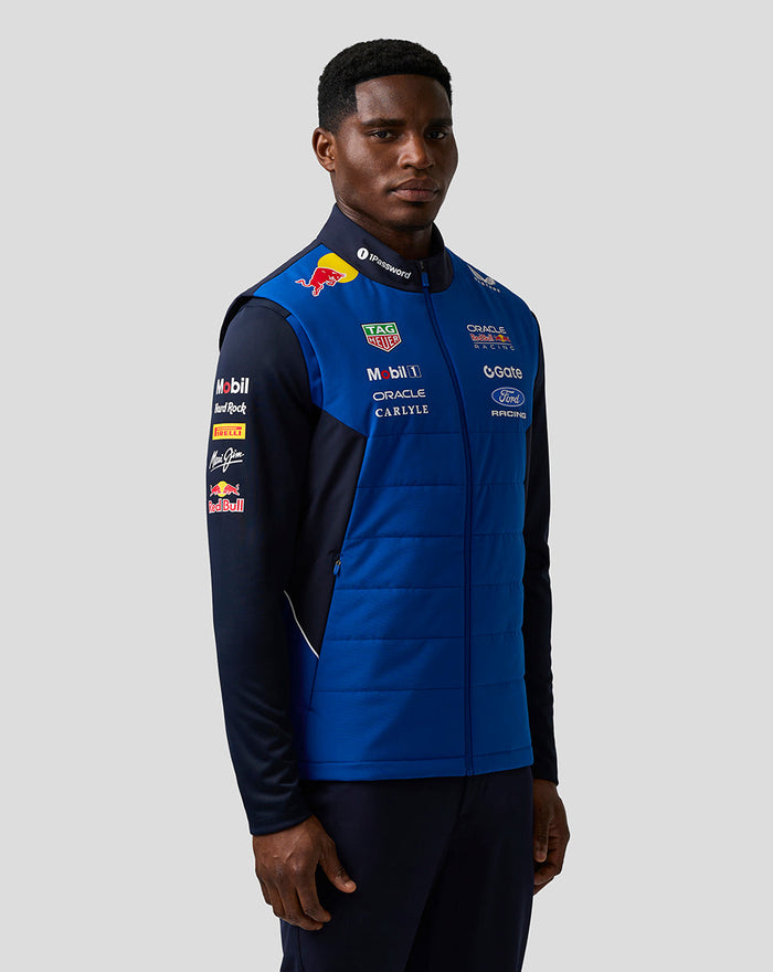 Male model wearing blue Night Sky Teamline Gilet shown from the side with racing sponsor logos.