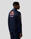 Male model seen from the back in a navy teamline midlayer with a large Red Bull logo and sponsor branding on the back and sleeve.